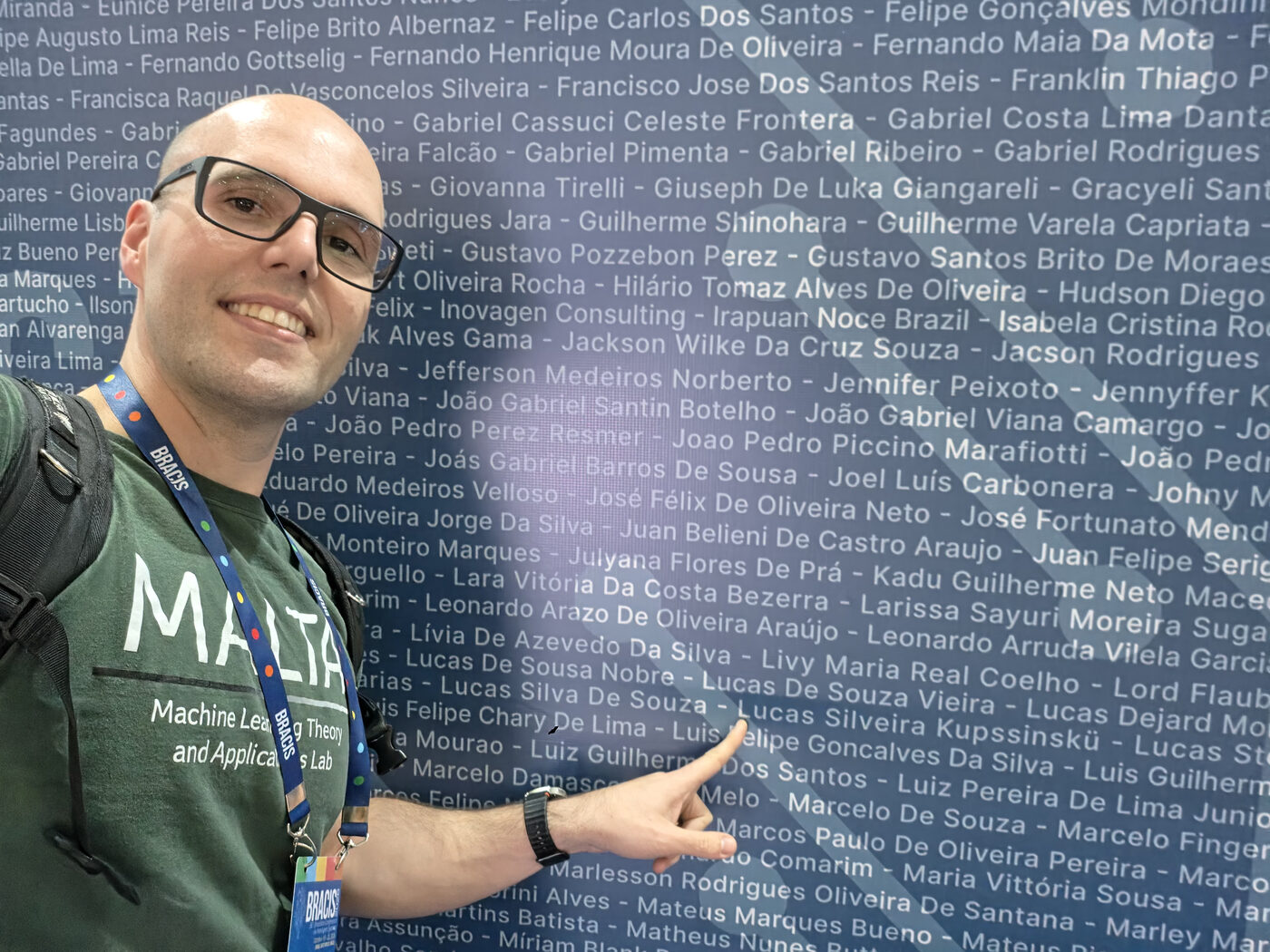 Lucas Kupssinskü pointing at his name on the BRACIS 2026 wall of participant names